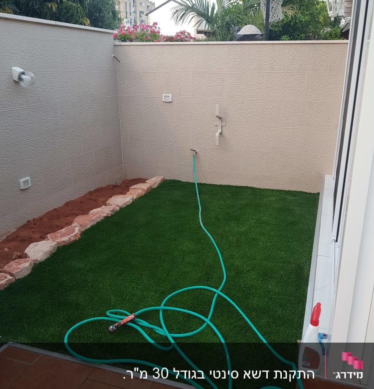 צינור מים על דשא מלאכותי בגינה קטנה